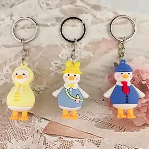 Three cute cartoon duck keychains in yellow raincoat, school and suit outfits