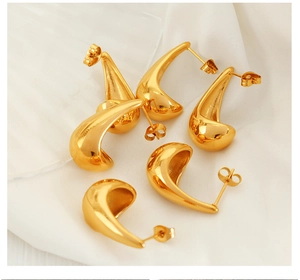 Detailed view of gold plated teardrop earrings on elegant white draped velvet fabric