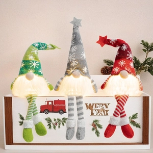 Three glowing Christmas gnomes with knitted hats and long legs on a rustic wooden box