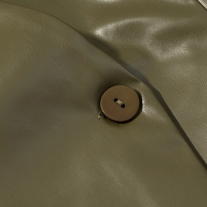 Detailed close-up of army green leather texture and brown button on a slim-fit jacket