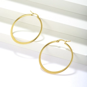 Close-up of polished gold large hoop earrings displayed on a minimalist geometric white background