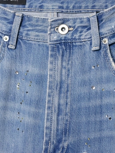 Gros plan de la taille d'un jean bleu avec strass brillants et bouton métallique