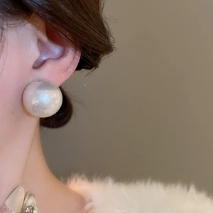 Gros plan d'élégantes boucles d'oreilles clous en perles blanches rondes au lustre irisé