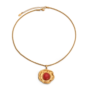 Nahaufnahme einer 18k Goldkette mit einem gehämmerten Anhänger und rotem Edelstein