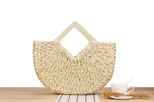 Detailed texture of hand-woven straw beach bag with gold thread and diamond wood handle