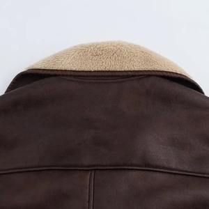 Detailed view of dark brown faux leather jacket with cream fleece collar and texture