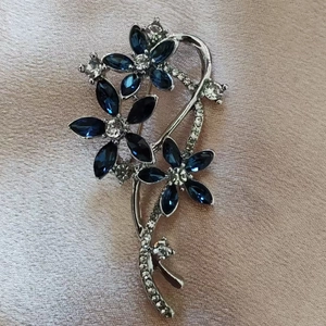 Close-up of elegant blue crystal flower brooch with silver stem on satin fabric