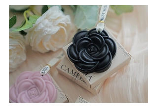 Dettaglio dei sacchetti di cera profumata alla camelia in nero e rosa con nastro regalo