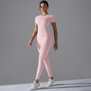 Set yoga rosa due pezzi con maglia a maniche corte aderente e leggings a vita alta in posa