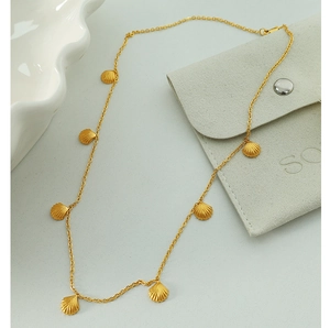 Detailed close-up of shell pendants on a golden French style chain with velvet bag