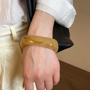 Macro shot of an irregular geometric amber resin bangle with a caramel marble texture