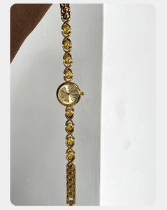 Détail d'une montre dorée avec bracelet en pierres jaunes et cadran romain élégant