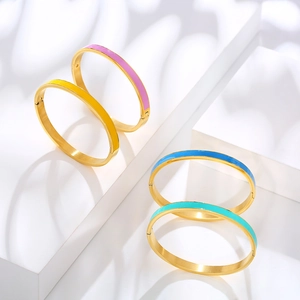 Detail of four colorful enamel bangles with 18k gold plating on white geometric blocks