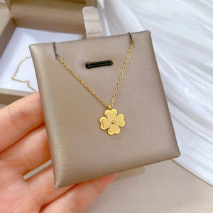Detailed macro shot of a gold-plated four-leaf clover pendant on a display cushion