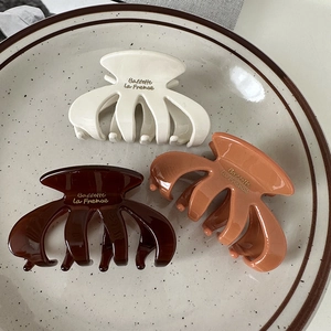 Detailed top view of three oval claw clips in cream and brown on a ceramic tray