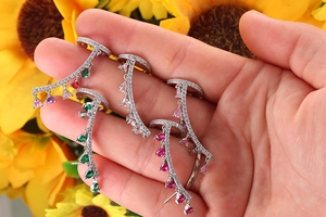 Dettaglio di orecchini lunghi in argento con zirconi colorati a goccia su montatura curva