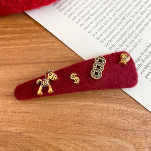 Close-up of a festive red wool felt hair clip with golden horse and wealth charms