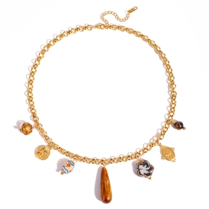 Macro detail of gold stainless steel necklace with amber glass and ceramic charms