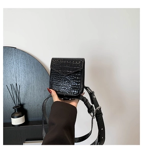 Détail d'un mini sac bandoulière noir avec motif crocodile et finition brillante
