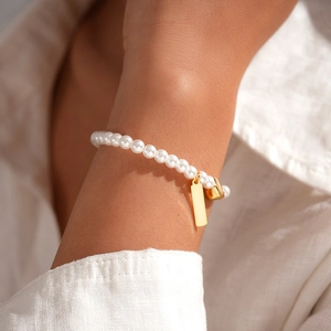 Close-up of elegant 18k gold plated pearl chain bracelet with square tag on wrist