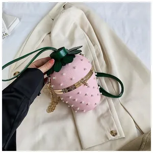Détail du sac seau en forme de fraise rose avec rivets perles et bandoulière chaîne