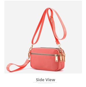 Detail view of pink nylon crossbody bag with three metal zipper compartments and strap