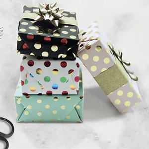 Polka dot gift wrapping paper rolls in black, white, mint, and lilac with gold foil accents