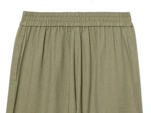 Detail of olive green trousers with elastic waistband and natural linen texture