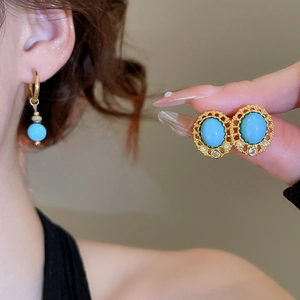 Detailed view of vintage gold earrings with turquoise stones and pearl accents