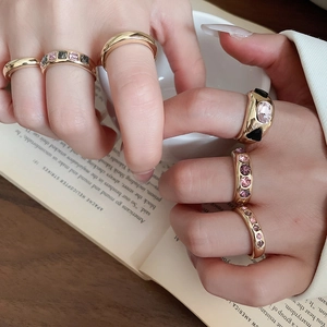Close-up of lifestyle hand model wearing geometric gold ring set with colorful gemstones