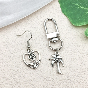Detail of silver alloy heart rose earring and palm tree keychain on textured background