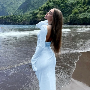 Dettaglio dell'elegante abito lungo bianco con schiena scoperta e maniche lunghe sulla spiaggia