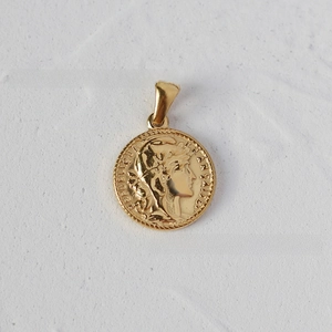 Detailed macro view of an 18K gold-plated coin pendant with a French relief design