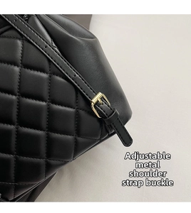 Detail of adjustable gold metal buckle on black quilted leather backpack strap