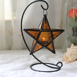 Macro view of amber glass star lantern hanging on a black iron crescent moon stand