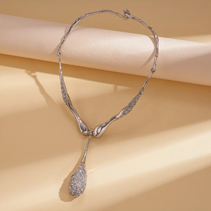 Macro detail of a silver irregular texture necklace with a sparkling teardrop pendant