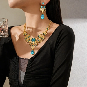 Vintage gold necklace and earring set with blue teardrop crystals and floral hollow design