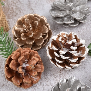 Golden, silver, and snow-tipped pine cone ornaments for Christmas tree window decor