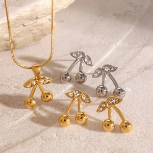 Set collana e orecchini a ciliegia dorata con zirconi su superficie in pietra chiara