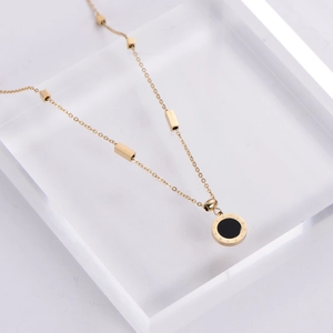 Gold necklace with Roman numeral circular pendant and black inlay on white background