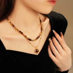 Dettaglio della collana a due strati dorata con occhio di tigre indossata da modella