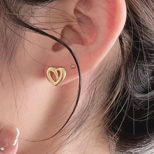 Close-up of a model wearing small 925 sterling silver hollow heart hoop earrings in gold