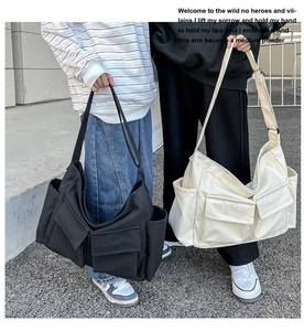 Detail view of large canvas messenger bags in black and beige with front flap pockets