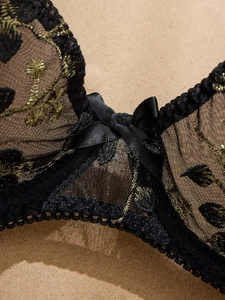 Gros plan d'un soutien-gorge en dentelle noire avec broderie florale dorée et nœud