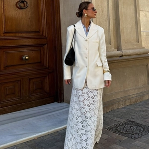 Street style view of high waist white lace skirt styled with a white blazer and black bag