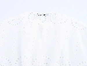 Macro detail of French white hollow-out embroidery and textured eyelet fabric pattern