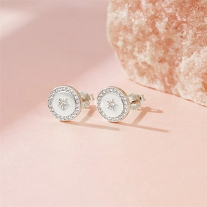 Macro detail of 925 silver stud earrings with white enamel star and zircon halo