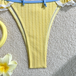 Close-up of yellow ribbed bikini bottom with blue drawstring and delicate white lace trim