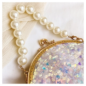 Detail of glitter sequins and white pearl handle on the gold frame mini evening bag