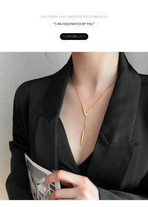 Close-up of minimalist gold V-shaped pendant necklace on a black blazer model